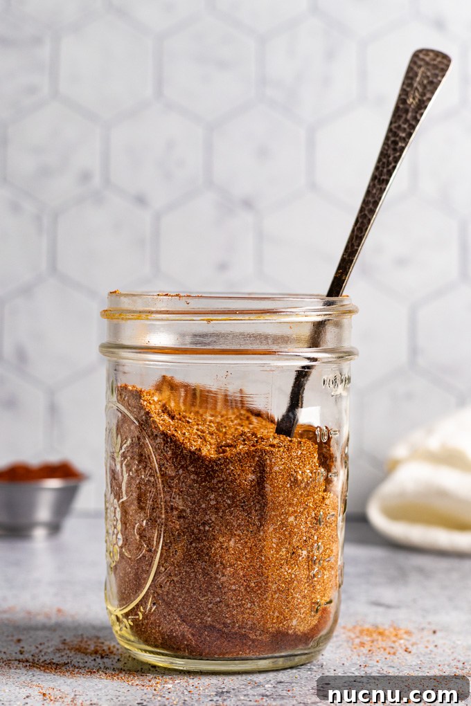 homemade fajita seasoning in a jar with a spoon sticking out of the jar.