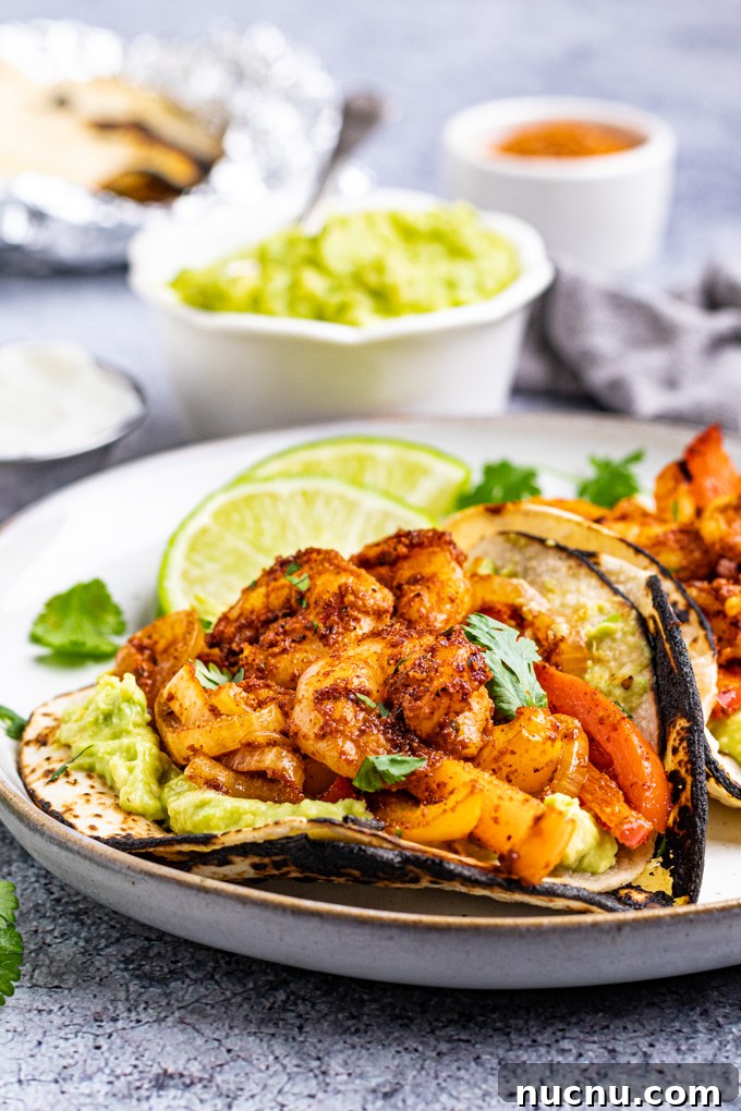Angled shot of sheet pan shrimp fajitas on a gray background.