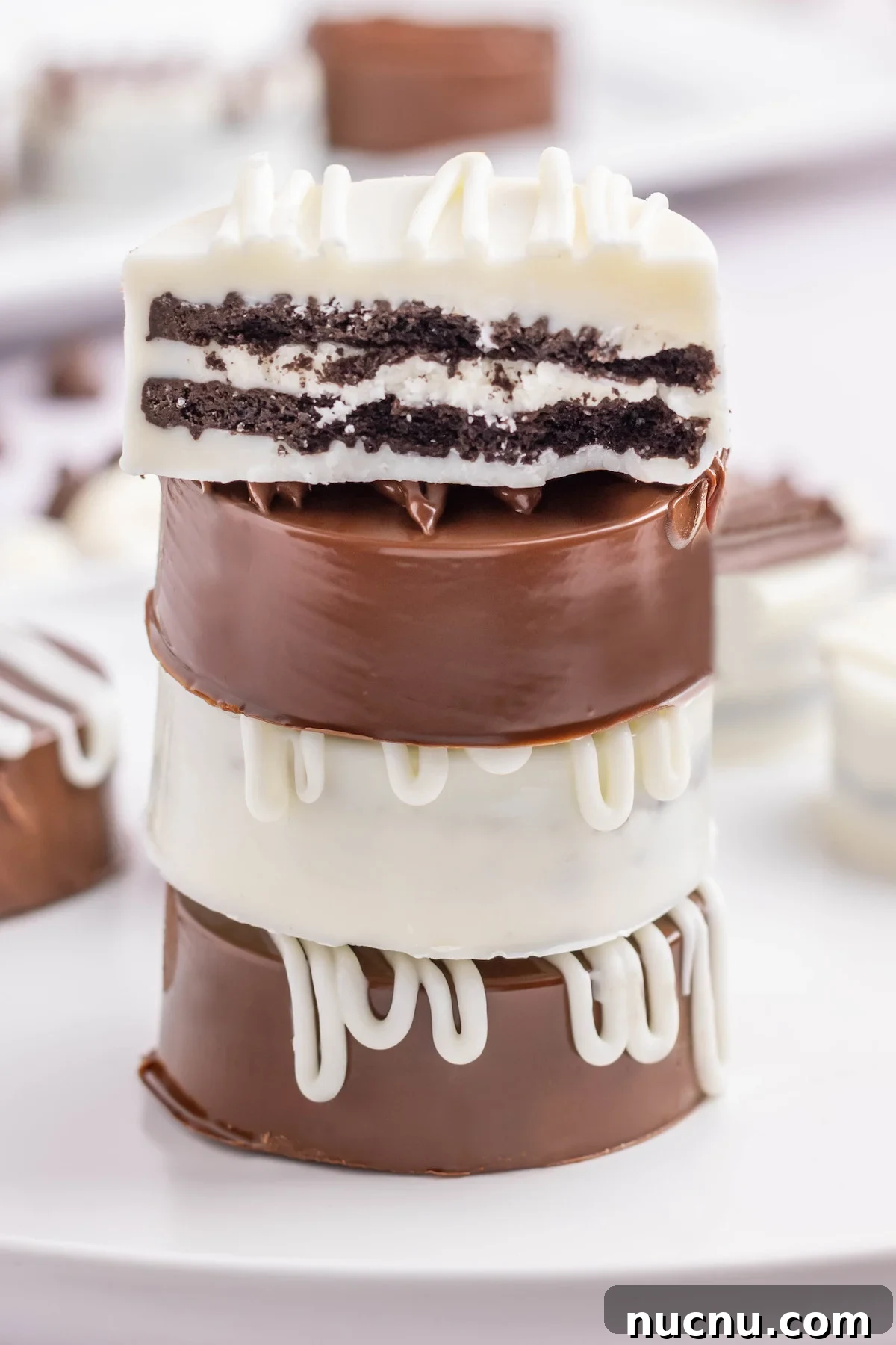 Ultimate Chocolate-Covered Oreos Recipe for Perfect Treats 7 Four white and milk chocolate covered Oreos stacked on top of each other. The top one is cut in half to see the cookie inside.
