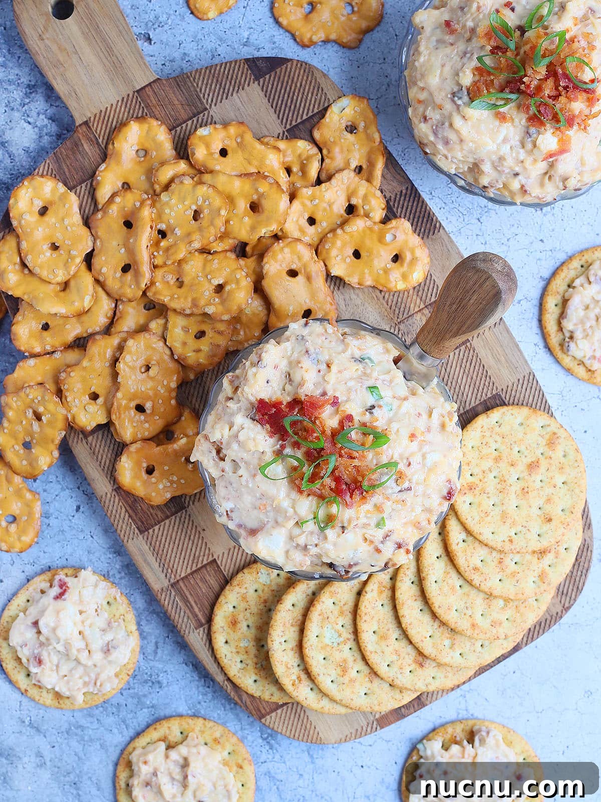 Spicy Chipotle Pimento Cheese Spread Recipe 2 Dish of spicy pimento cheese topped with chopped bacon and green onions surrounded by pretzels and crackers.