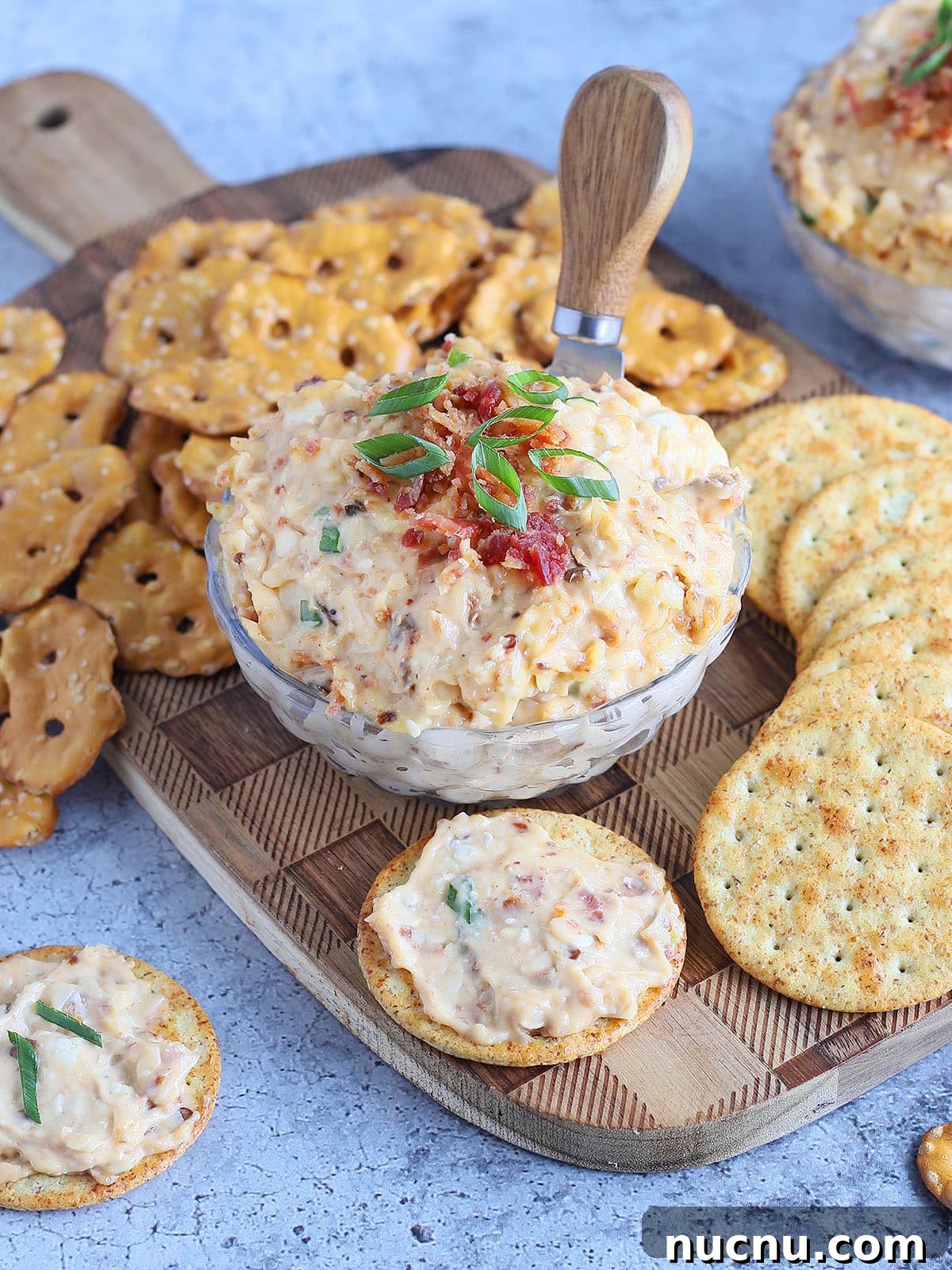 Spicy Chipotle Pimento Cheese Spread Recipe 7 Dish of spicy pimento cheese topped with chopped bacon and green onions surrounded by pretzels and crackers.