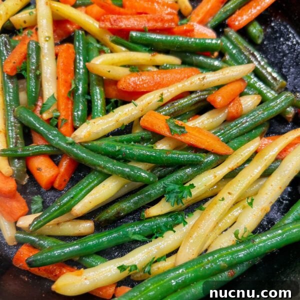 mix of long green and yellow beans and carrots in cast iron pan
