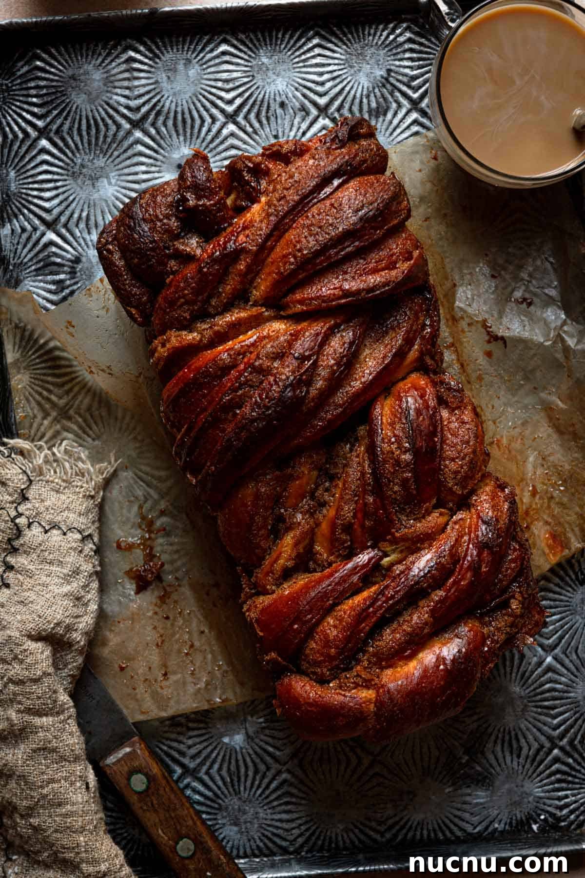 Cinnamon babka on a pan with a coffee cup.