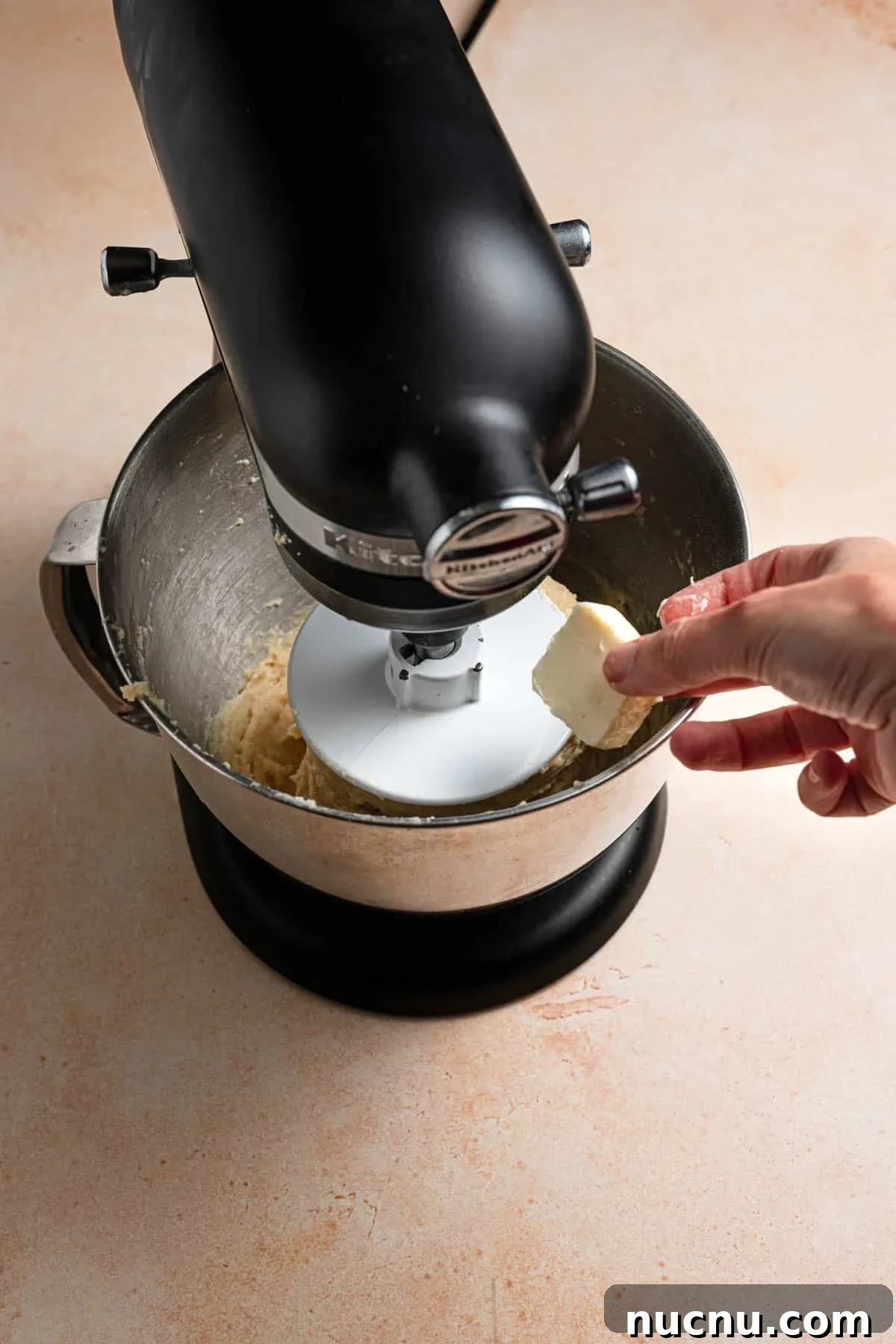 Adding butter to a dough in a stand mixer.