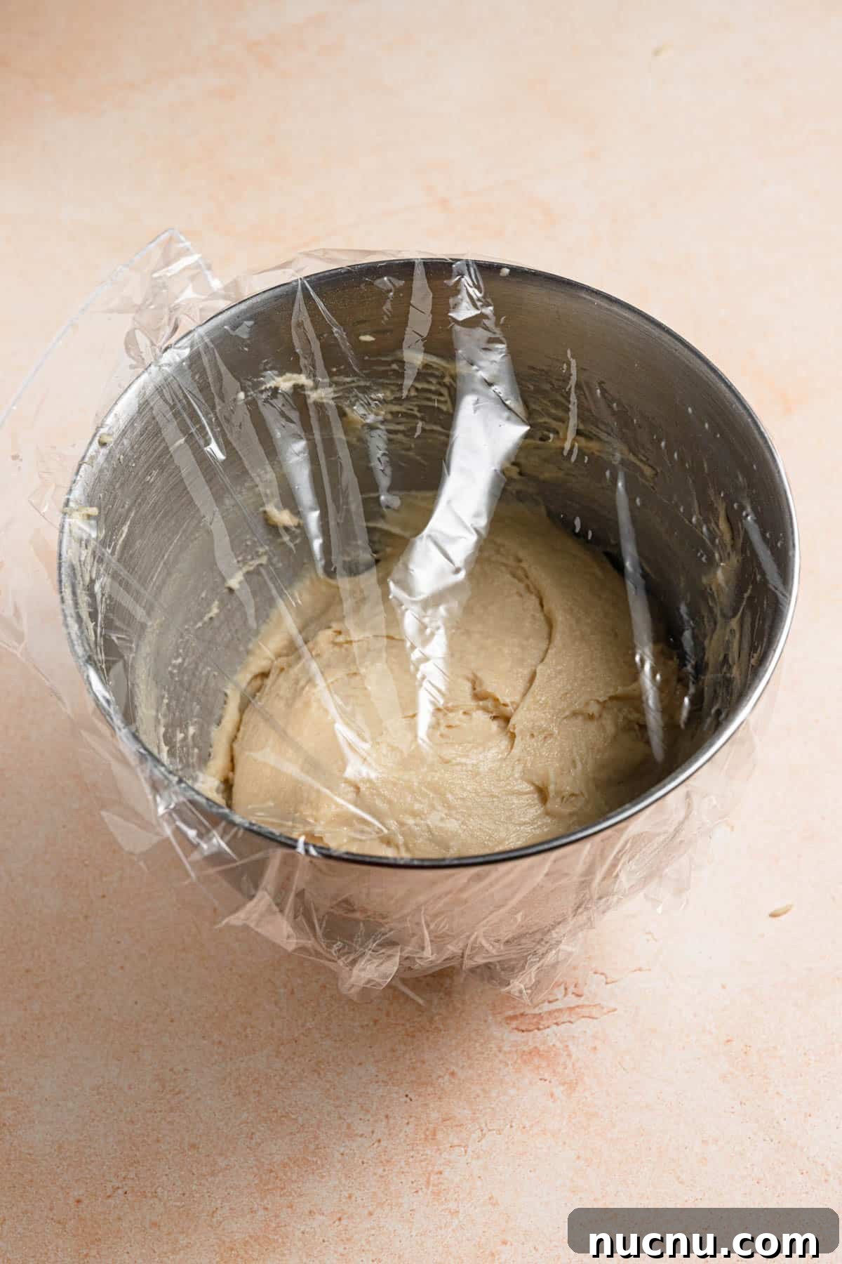 Buttery dough in a bowl with plastic wrap.