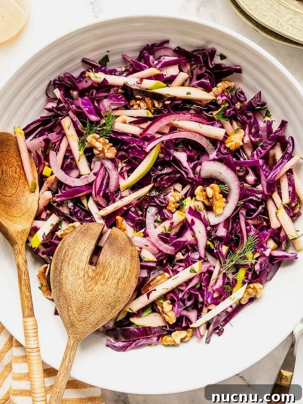 Purple cabbage slaw with apples and walnuts in a bowl.