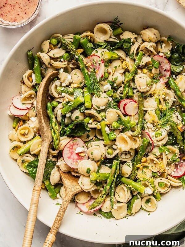 Bowl of spring pasta salad loaded with asparagus, radish, spinach, herbs and a tangy sumac honey dressing.