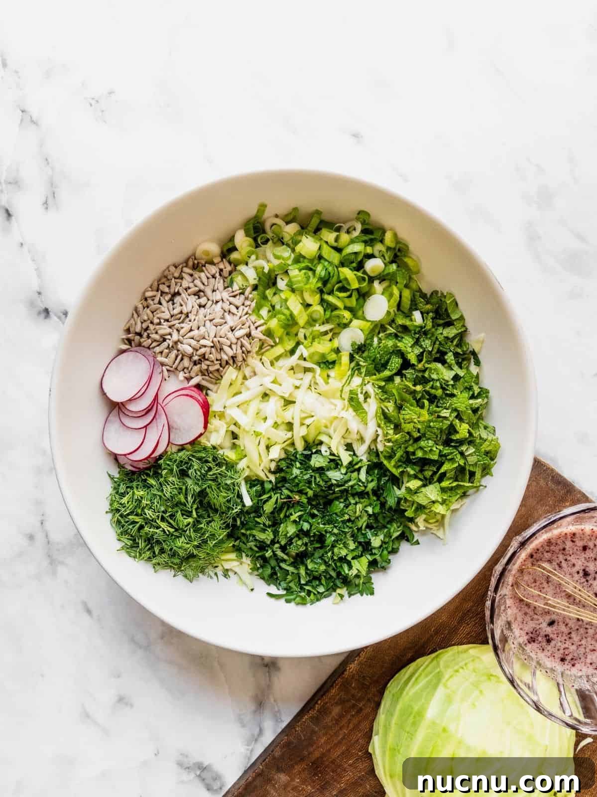 Lemon Sumac Coleslaw (No Mayo) — Tangy, Fresh Side Dish 7 Large salad bowl with shredded cabbage, sliced radish, sunflower seeds and fresh herbs.