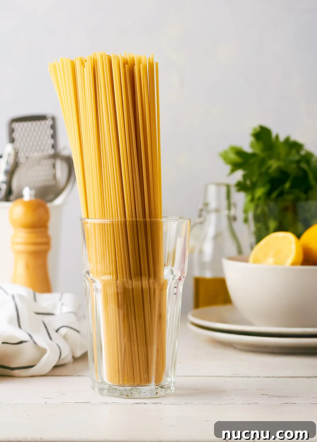 Creamy Lemon Spaghetti Recipe: Zesty, Silky Pasta in 20 Minutes 8 A glass filled with uncooked spaghetti stands on a white kitchen table