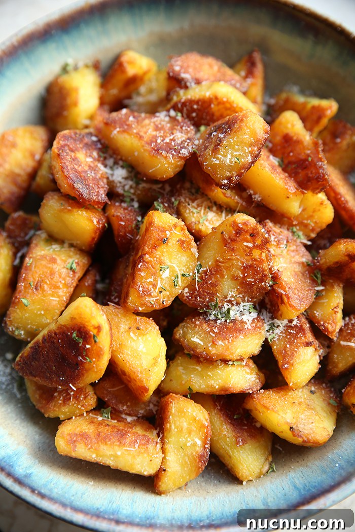 How to Make Extra-Crispy Roasted Potatoes 2 A large bowl of extra crispy roasted potatoes tossed with grated parmesan cheese and dried parsley.