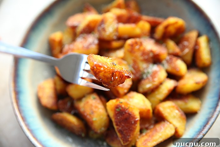 How to Make Extra-Crispy Roasted Potatoes 4 A fork with a crispy potato cube held above a serving bowl of crispy potato cubes.