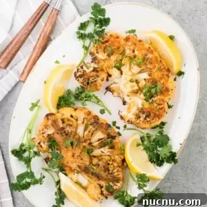Roasted Cauliflower Steaks with Garlic and Herb Butter 7 oven roasted cauliflower steaks with lemon slices on a platter