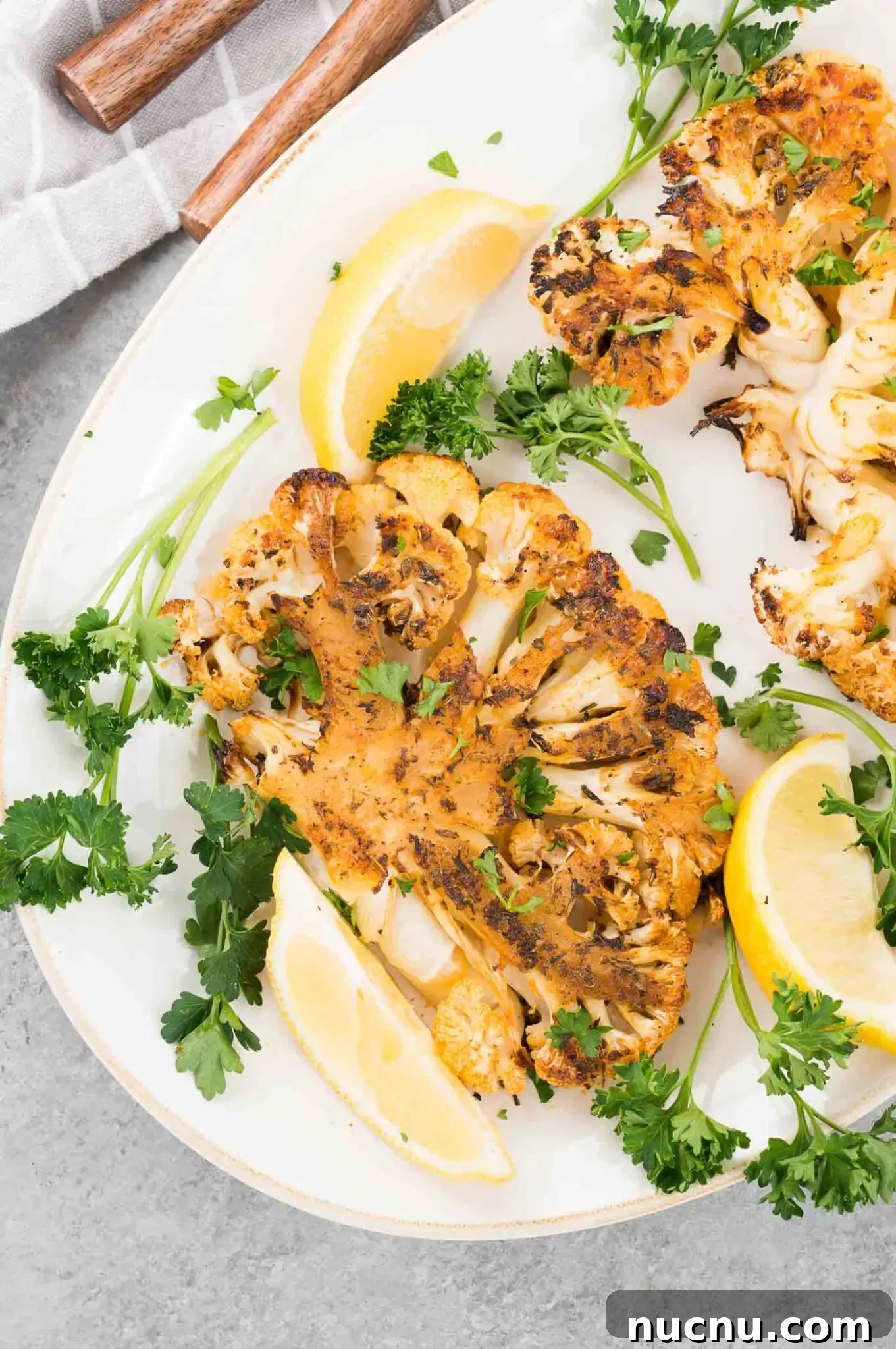 Roasted Cauliflower Steaks with Garlic and Herb Butter 9 cauliflower slices and lemon wedges on a plate