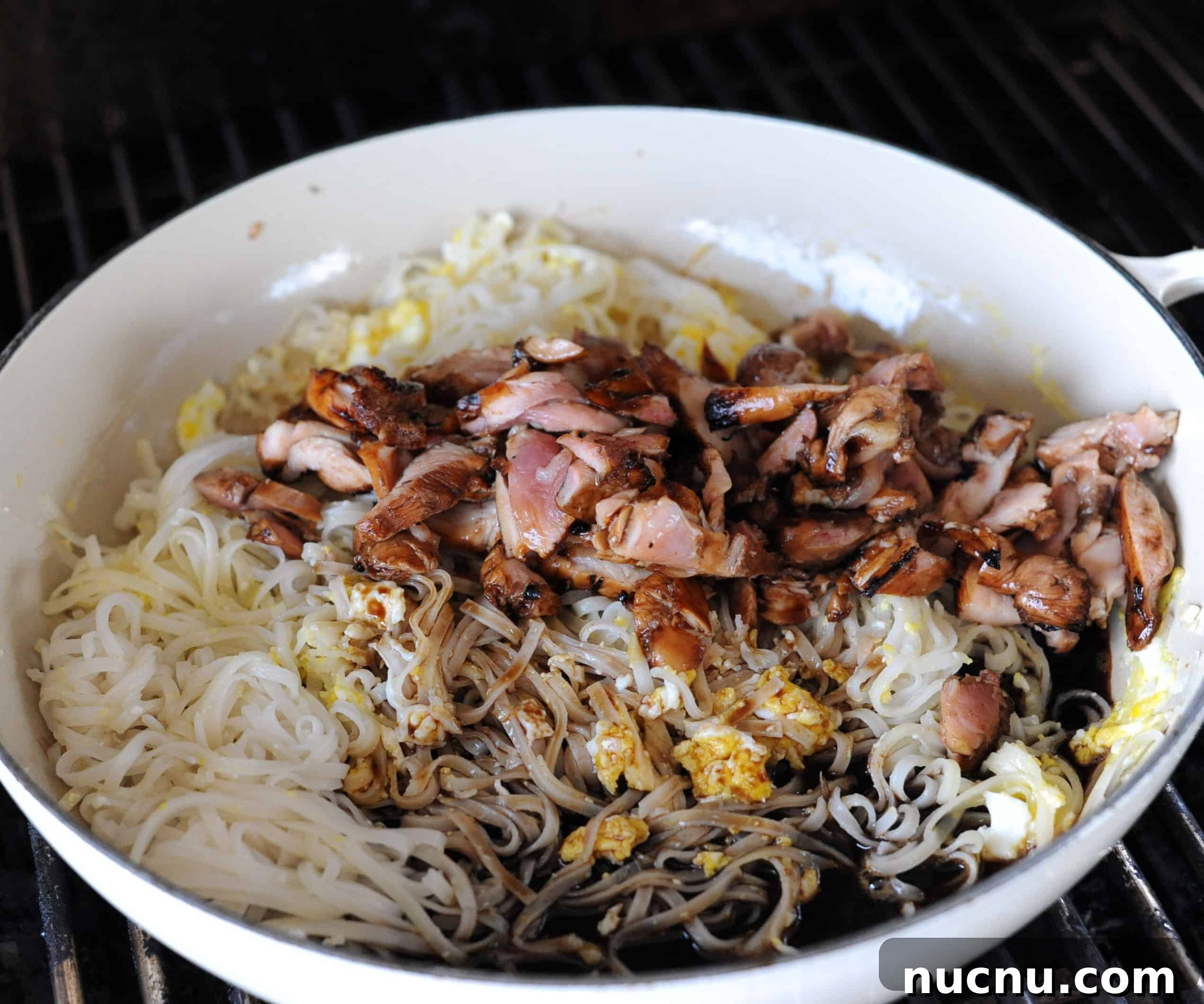 Grilled Pad Thai Recipe: Smoky Stir-Fried Noodles with Shrimp and Peanuts 7 a skillet with rice noodles, cooked eggs, chicken and marinade.