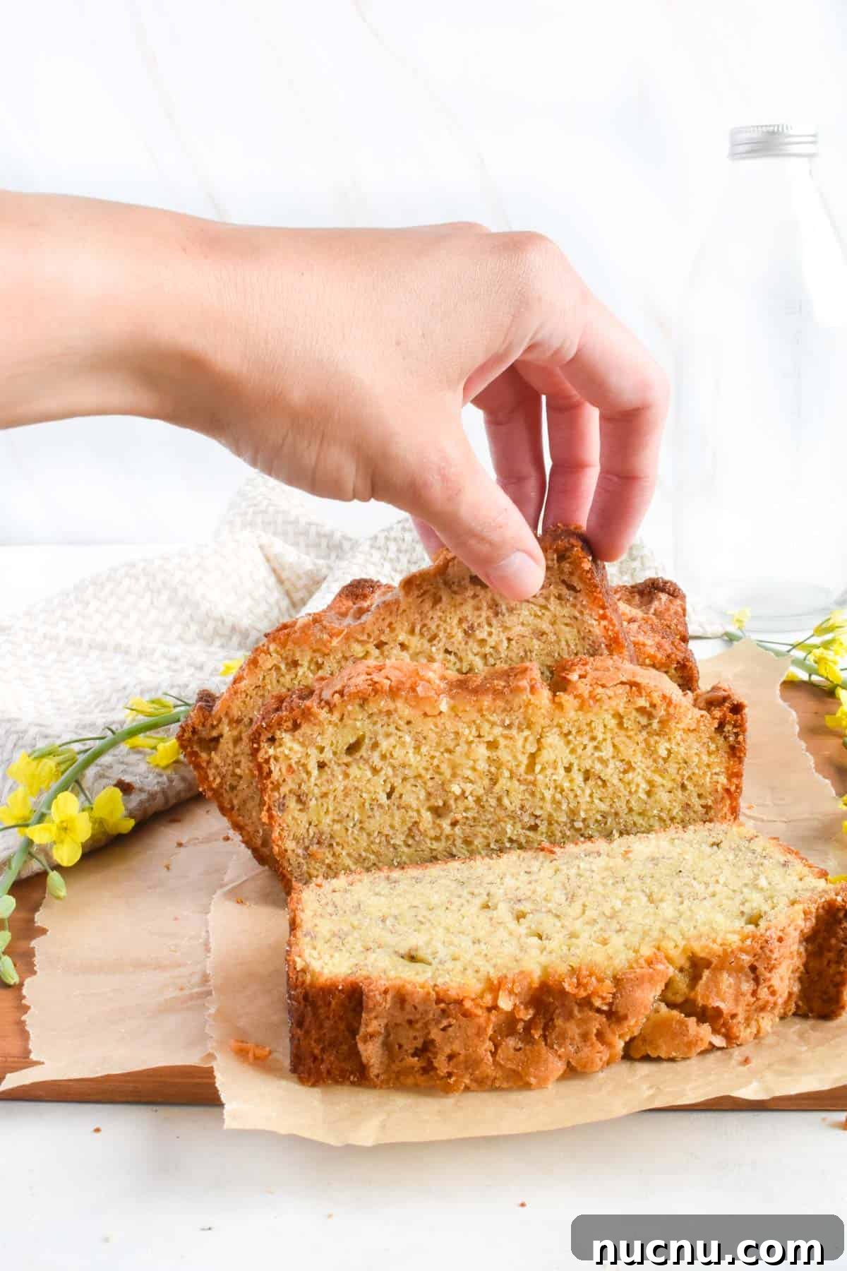 Moist Banana Bread Without Baking Soda: Simple Oven Recipe 12 hand picking up slice of banana bread.