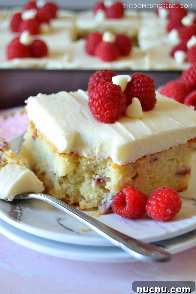 White Chocolate Raspberry Layer Cake Recipe for Celebrations 5 slice of white choc raspberry cake with a bite missing on a white plate