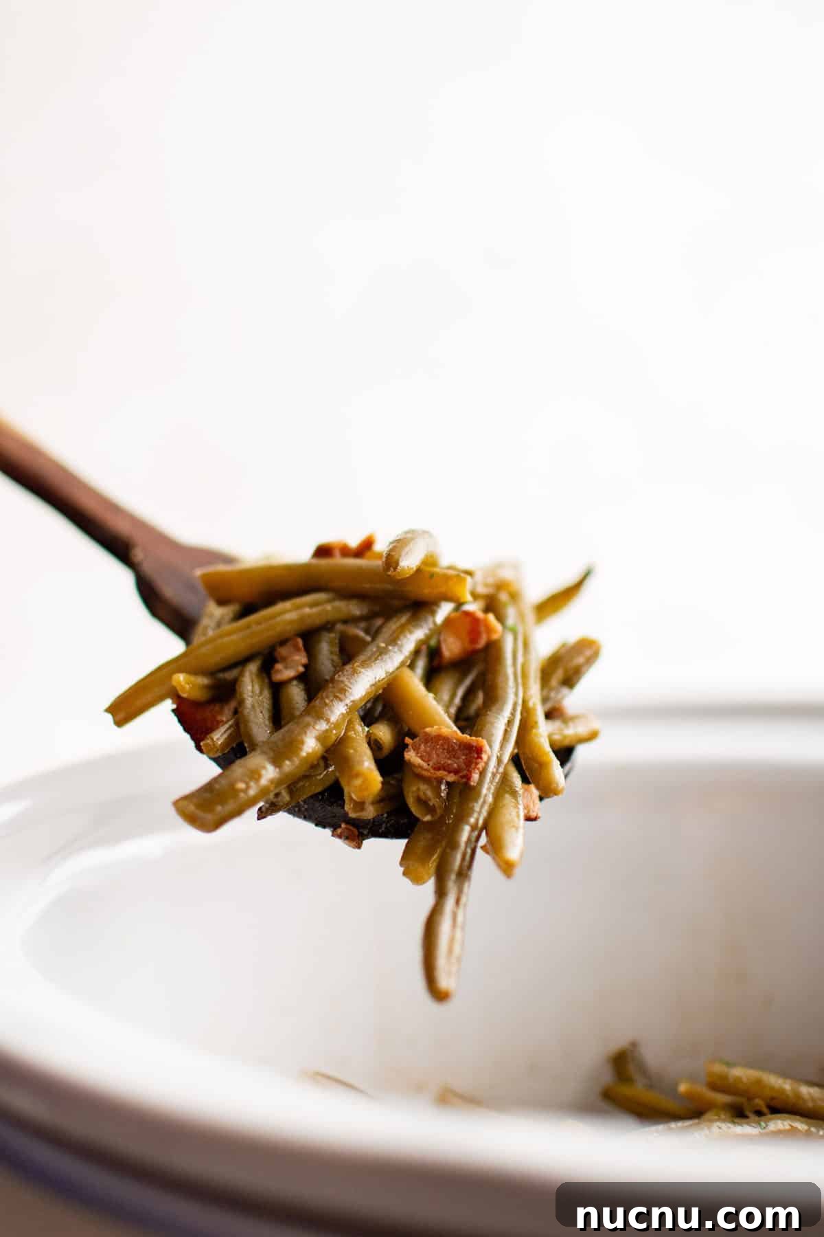 Slow-Cooked Garlic Green Beans in the Crockpot 4 crockpot green beans on a wooden serving spoon