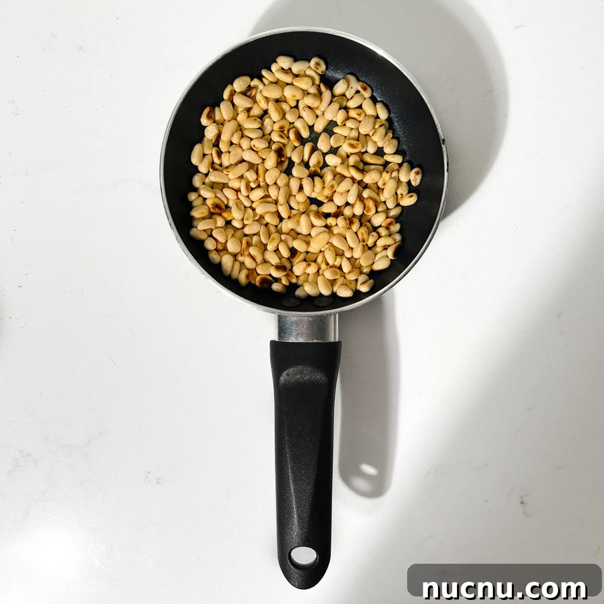 Arugula Pesto: Quick Recipe for Peppery Homemade Sauce 4 Toasting pine nuts in a small pan.