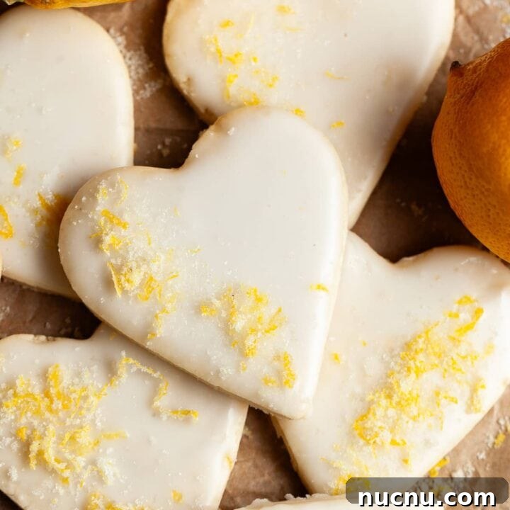 gluten free lemon sugar cookies topped with lemon glaze and lemon sugar on brown parchment paper