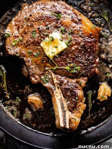 overhead shot of a ribeye steak cooking in a cast iron skillet