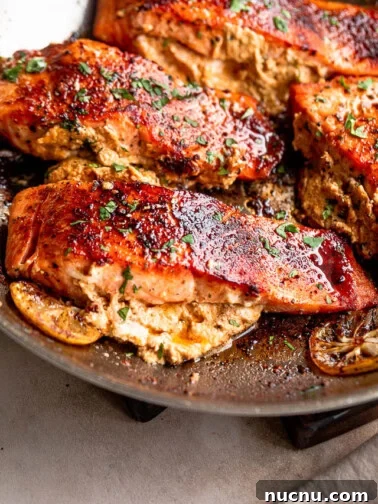 Salmon fillets cooking in a skillet.