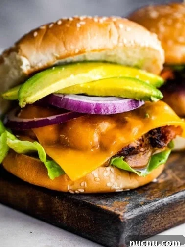 turkey burger with cheese, avocado, and a slice of red onion, set in between sesame seed buns