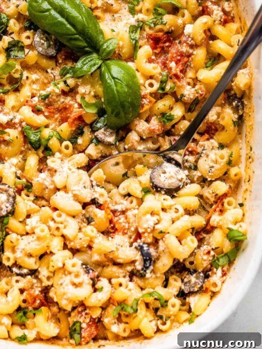 spooning out baked feta pasta from baking dish