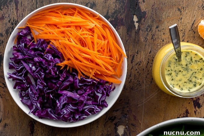 Winter Citrus Salad with Honey Dressing and Toasted Almonds 4 Shredded carrot and red cabbage on a plate next to a jar of dressing.