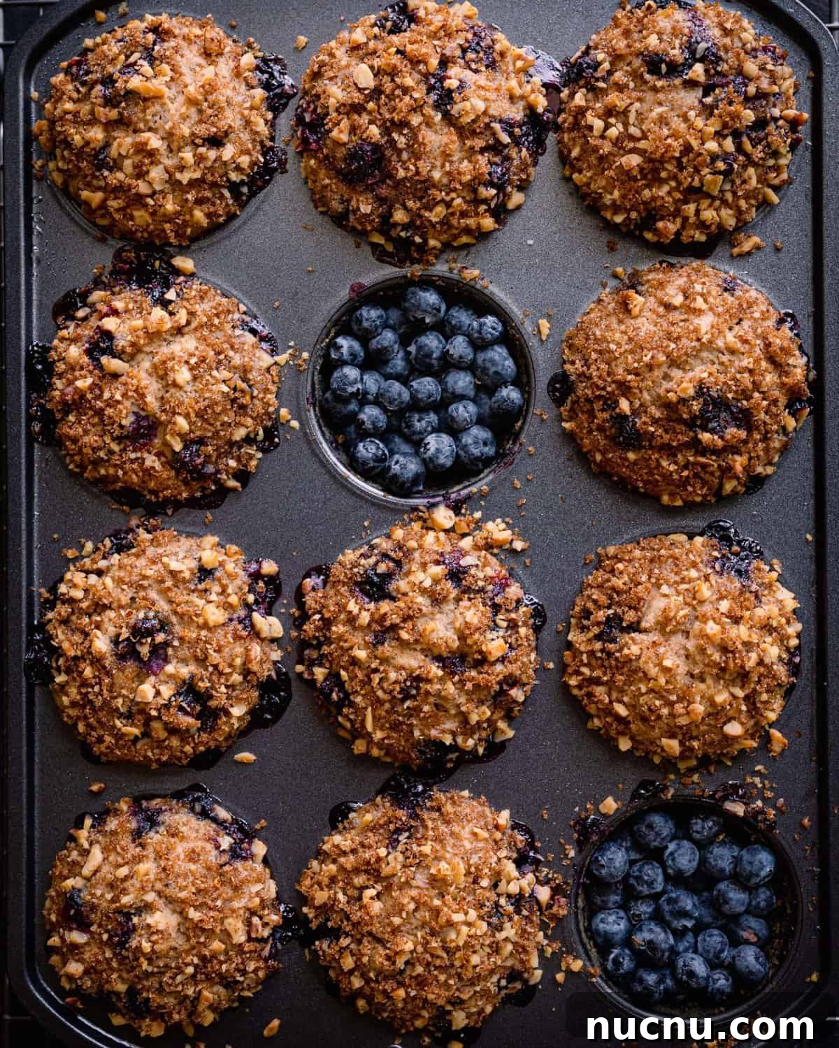 Vegan Blueberry Muffins Recipe: Moist, Fluffy, Simple to Make 13 vegan blueberry muffins in muffin tin, with two muffins removed and filled with blueberries.