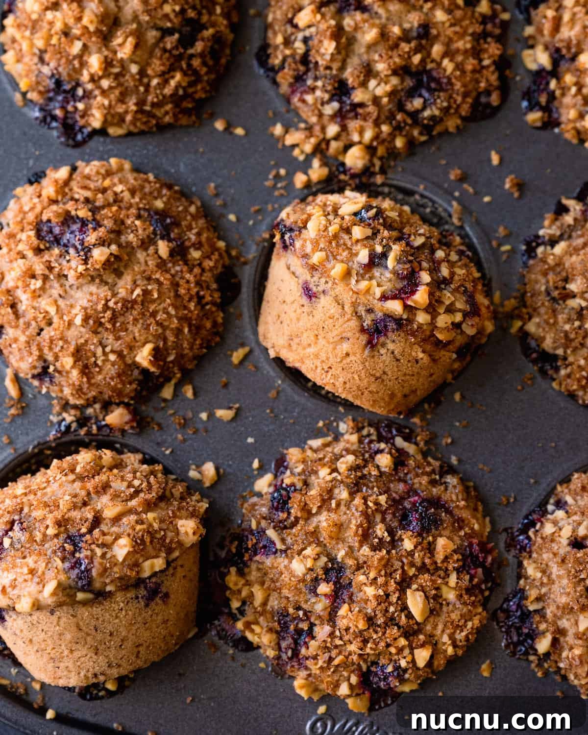 Vegan Blueberry Muffins Recipe: Moist, Fluffy, Simple to Make 15 closeup of vegan blueberry muffins with walnut brown sugar crumble in muffin tin.
