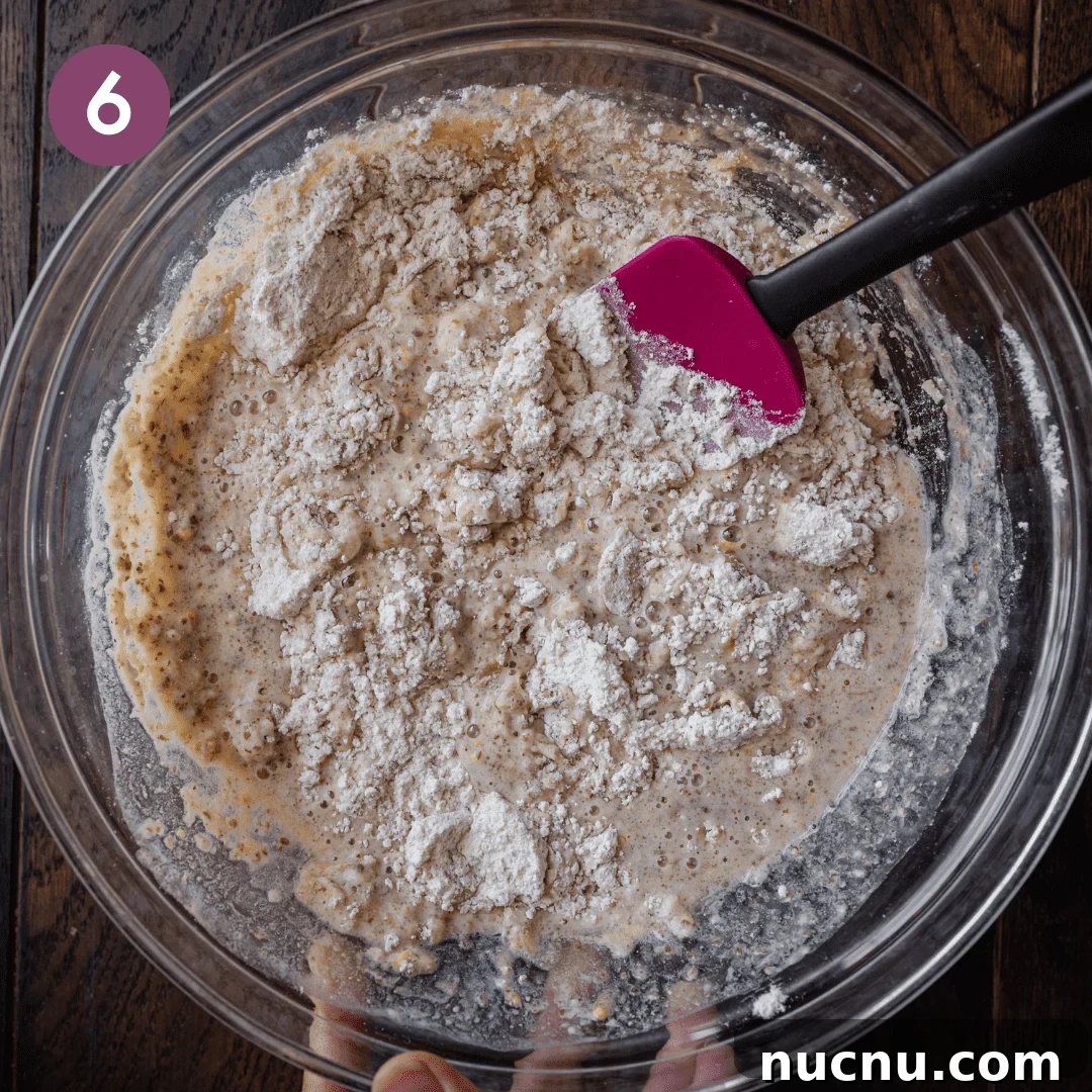 Vegan Blueberry Muffins Recipe: Moist, Fluffy, Simple to Make 10 mixing dry and wet ingredients for muffin batter in glass bowl with silicone spatula.