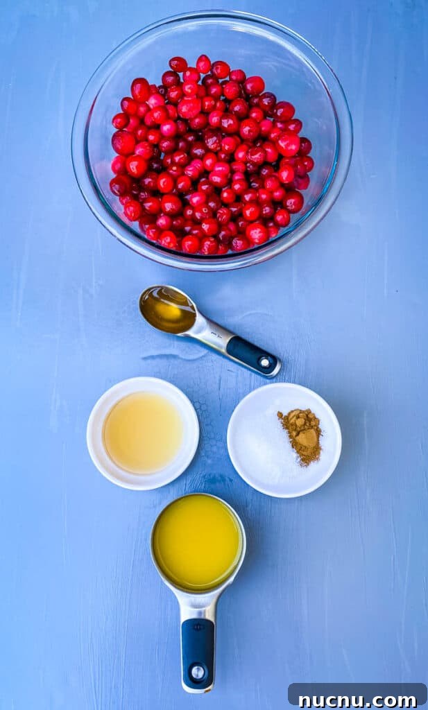 Grand Marnier Cranberry Sauce Recipe for Holiday Dinners 5 cranberries in a glass bowl alongside orange juice, honey, cinnamon, and sweetener