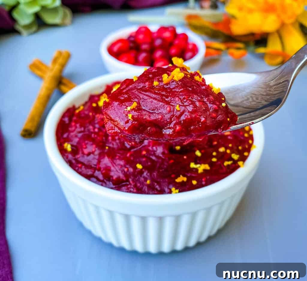 Grand Marnier Cranberry Sauce Recipe for Holiday Dinners 10 person holding a spoon of Grand Marnier cranberry sauce