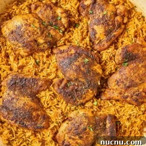 One-Pan Shawarma Chicken and Rice Skillet Recipe 13 A pan of Shawarma Chicken and Rice Skillet features seasoned, baked chicken thighs atop spiced yellow rice, finished with a sprinkle of fresh herbs.