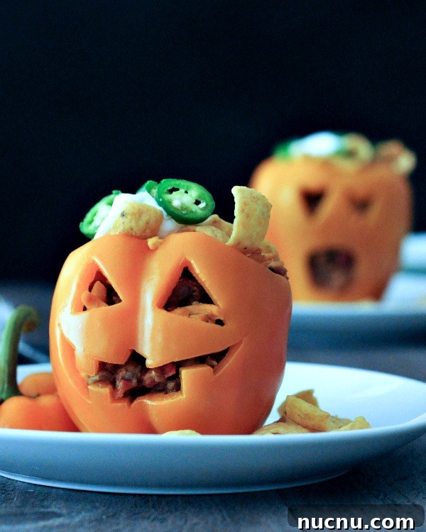 stuffed pepper jack o lanterns two orange bell peppers carved into a halloween jack o lantern, filled with Frito pie (chili and fritos)