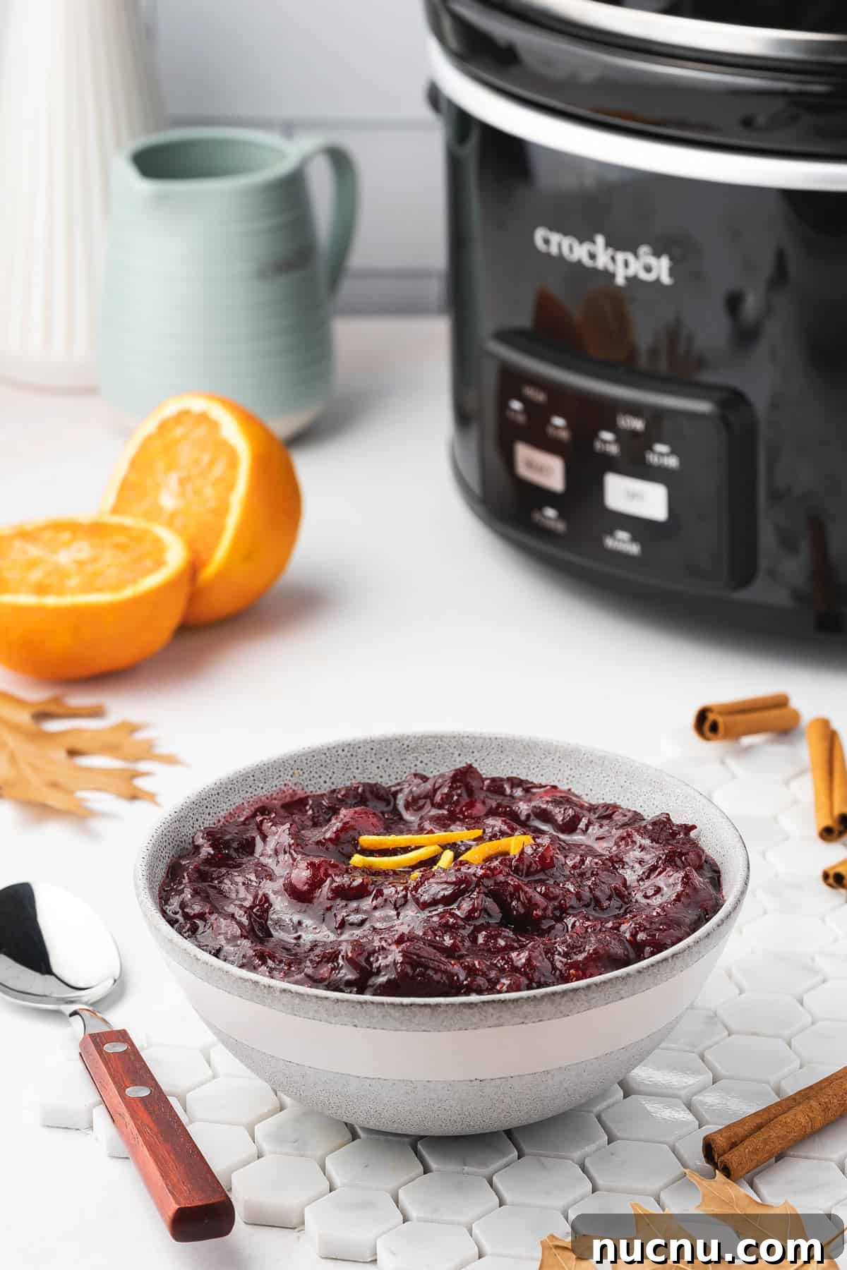Slow-Cooker Cranberry Sauce for Thanksgiving and Holidays 7 A bowl of cranberry sauce with a crockpot in the background.
