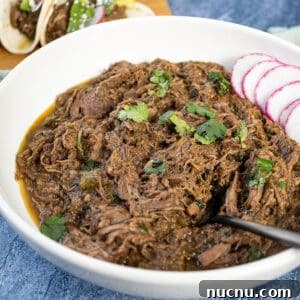 Dutch Oven Barbacoa Tacos Recipe — Tender Slow-Cooked Beef Tacos 14 Barbacoa in a bowl topped with cilantro.