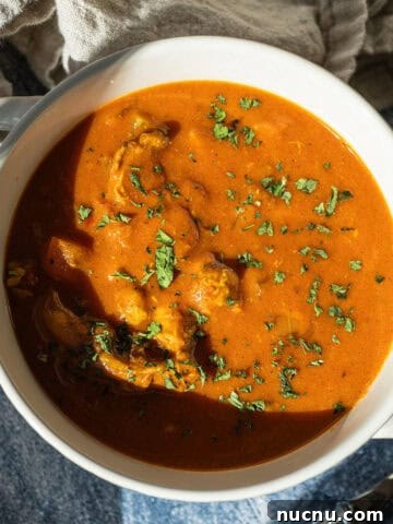 Butter chicken soup in a bowl topped with cilantro.