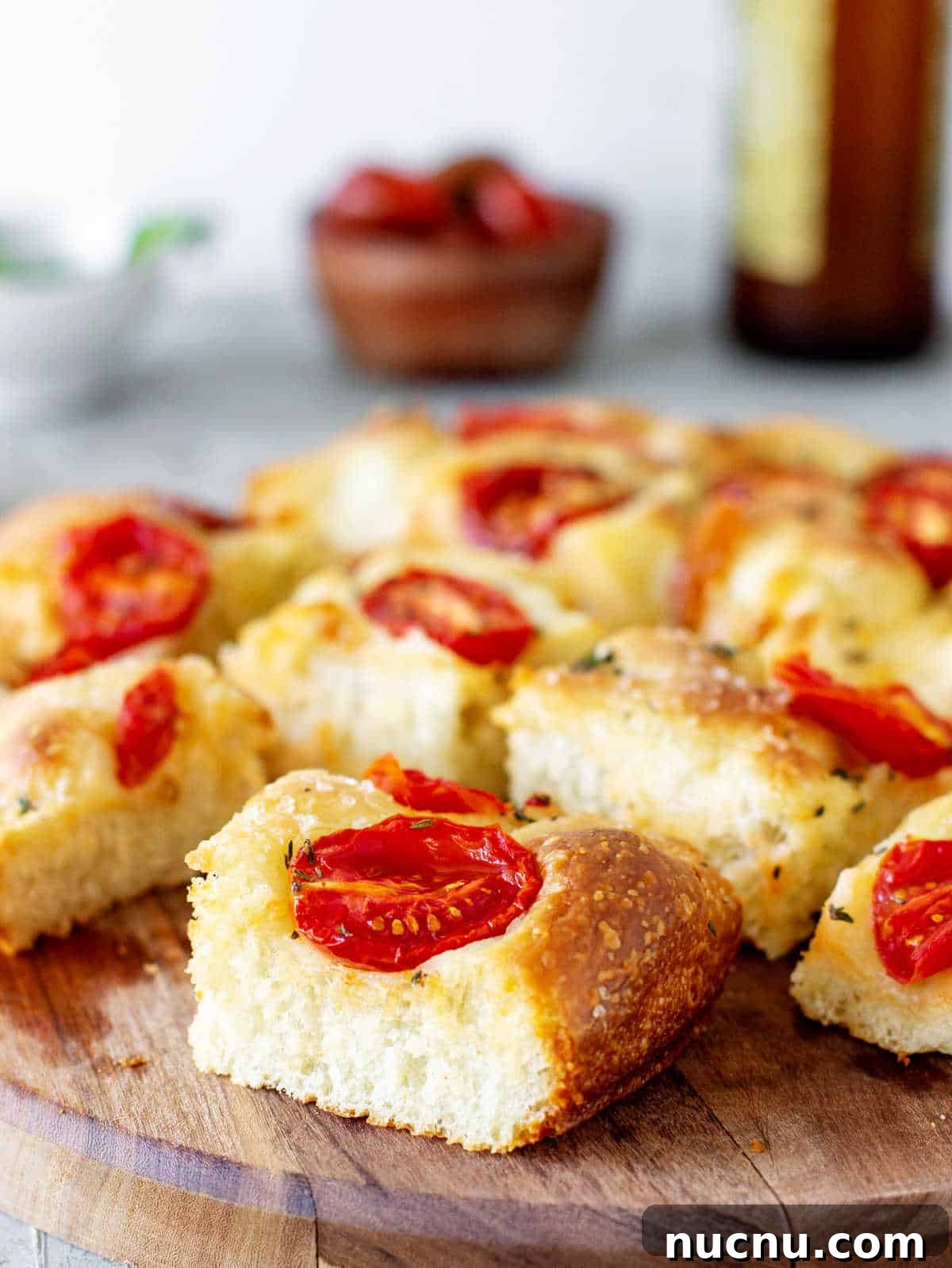 Tomato Focaccia Recipe with Step-by-Step Video Tutorial 9 Wooden board with tomato focaccia pieces.