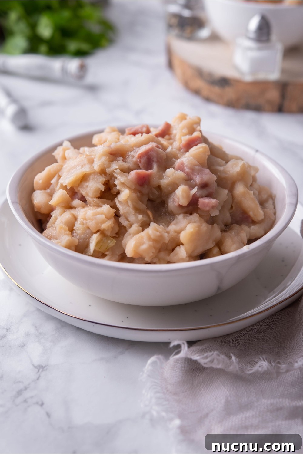 Copycat Grandma Brown's Baked Beans Recipe You’ll Love 10 Grandma Browns baked beans in a white bowl atop a white plate.