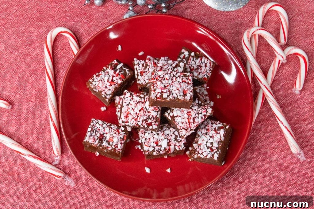 Decadent Chocolate Peppermint Fudge Recipe for the Holidays 5 Peppermint fudge on a red plate with scattered candy canes.