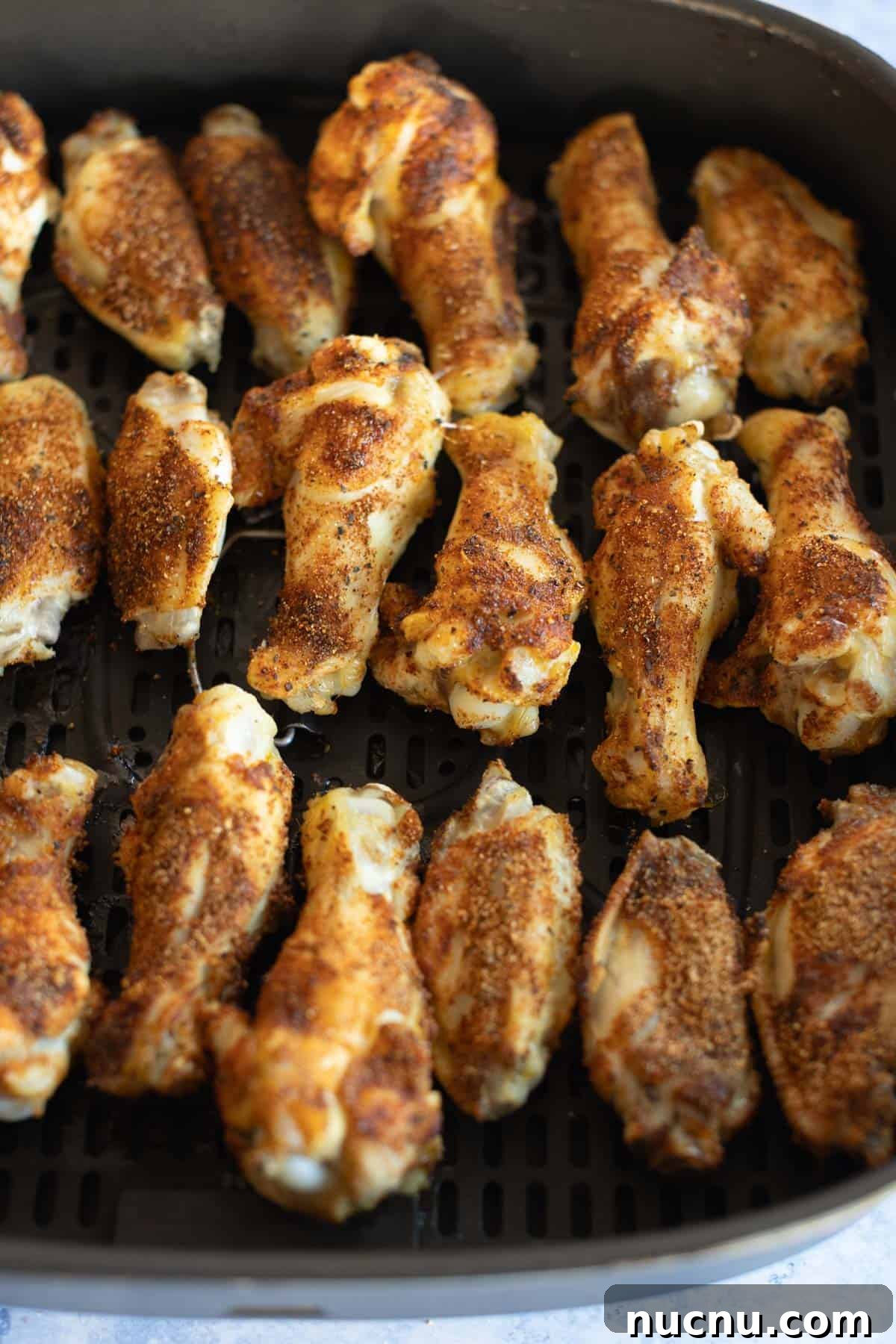 Crispy Dry-Rub Wings Recipe for Perfectly Spiced Chicken 11 Dry rub chicken drumsticks with seasoning on an air fryer tray.