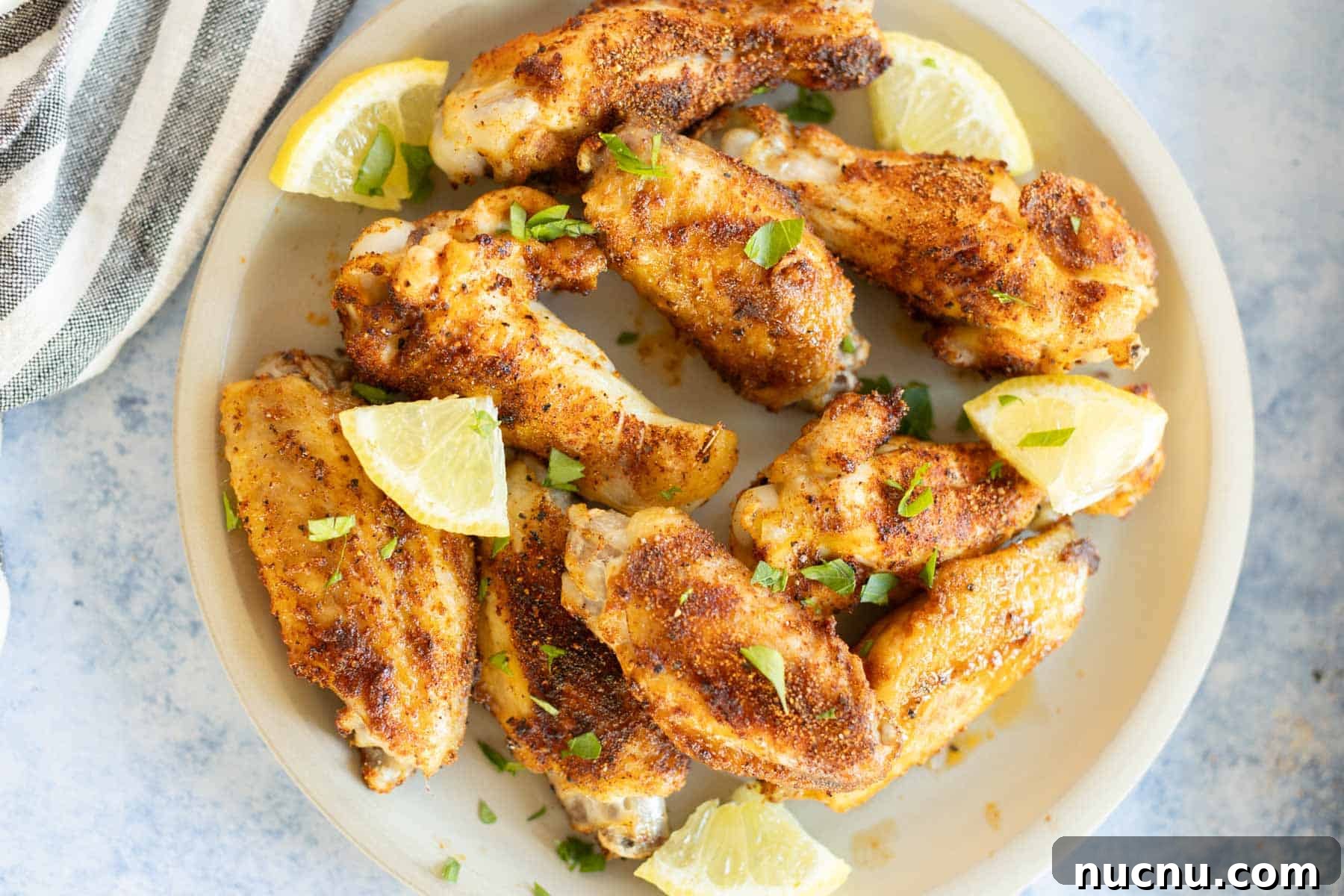 Crispy Dry-Rub Wings Recipe for Perfectly Spiced Chicken 4 A plate of dry rub chicken wings garnished with lime wedges and chopped parsley.