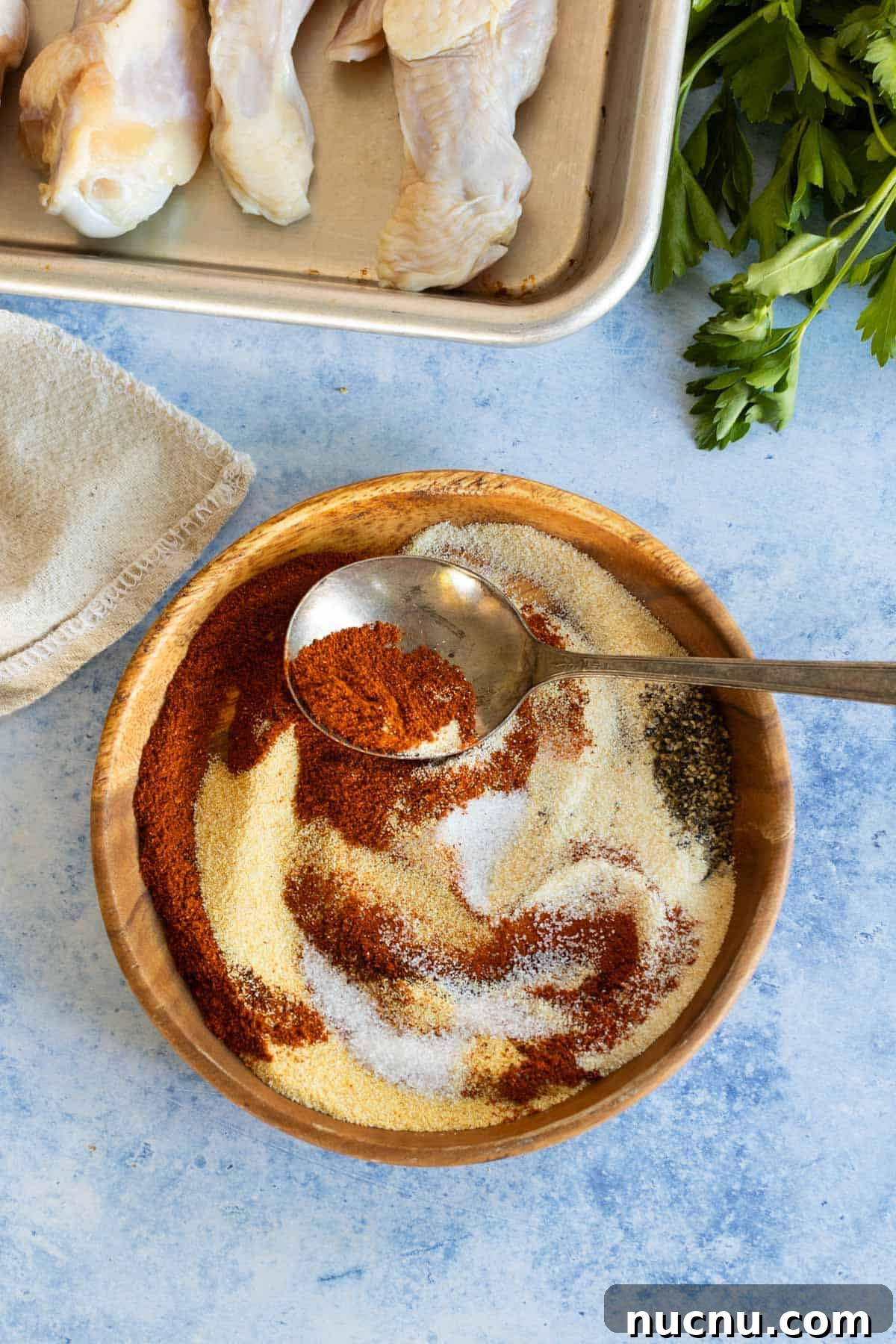 Crispy Dry-Rub Wings Recipe for Perfectly Spiced Chicken 5 A wooden bowl with a chicken dry rub mixed together with a spoon.