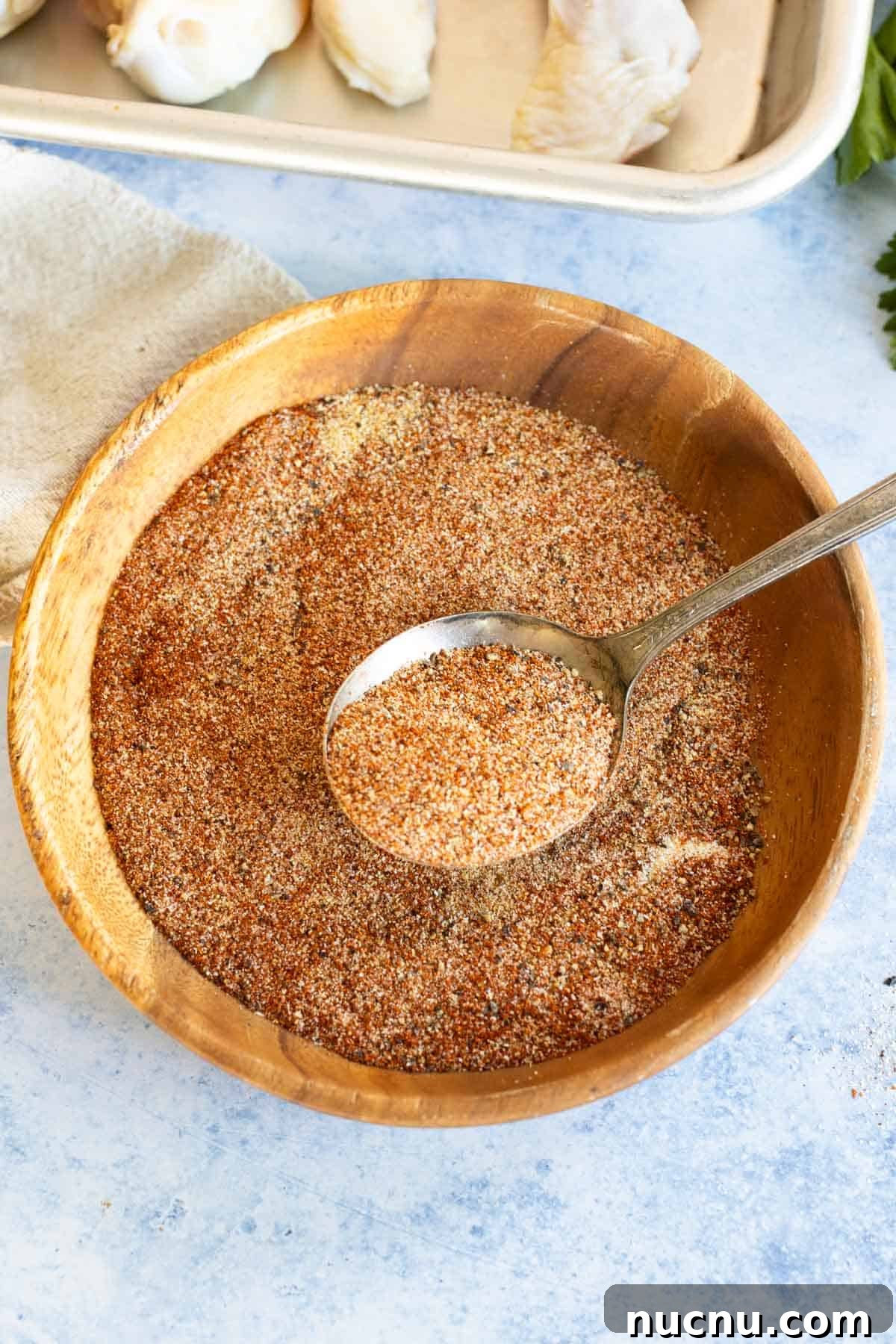 Crispy Dry-Rub Wings Recipe for Perfectly Spiced Chicken 6 A chicken wing dry rub being scooped out of a wooden bowl with a spoon.