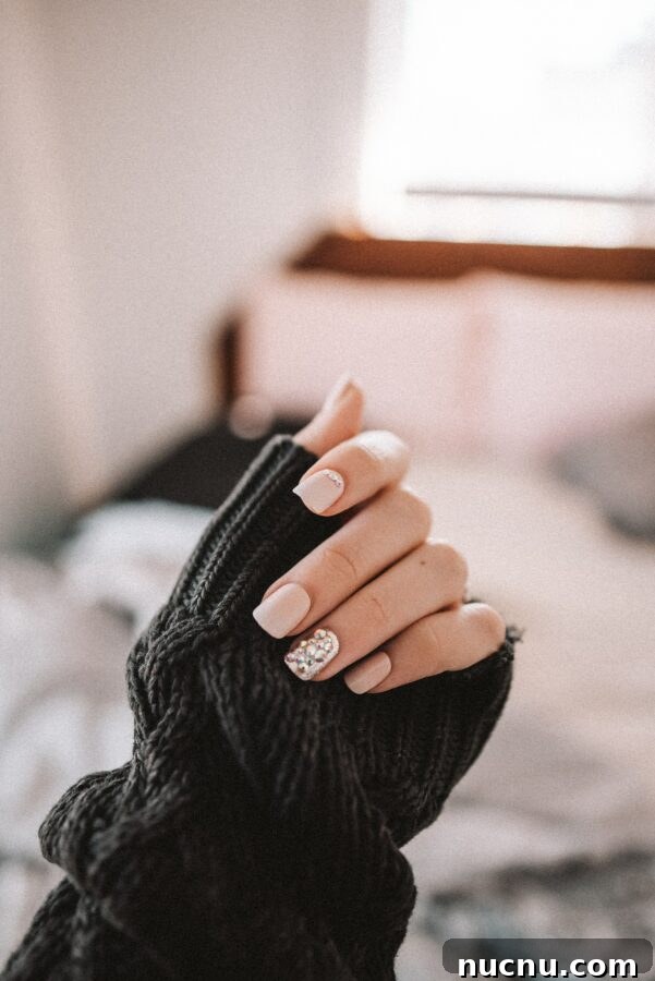 hand holding sweater cuff acrylic nails at home.