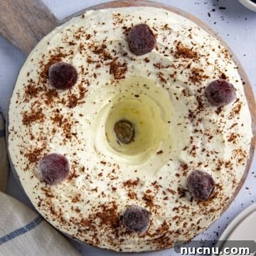 whole baked and frosted cake with chocolate shavings and cherries on top