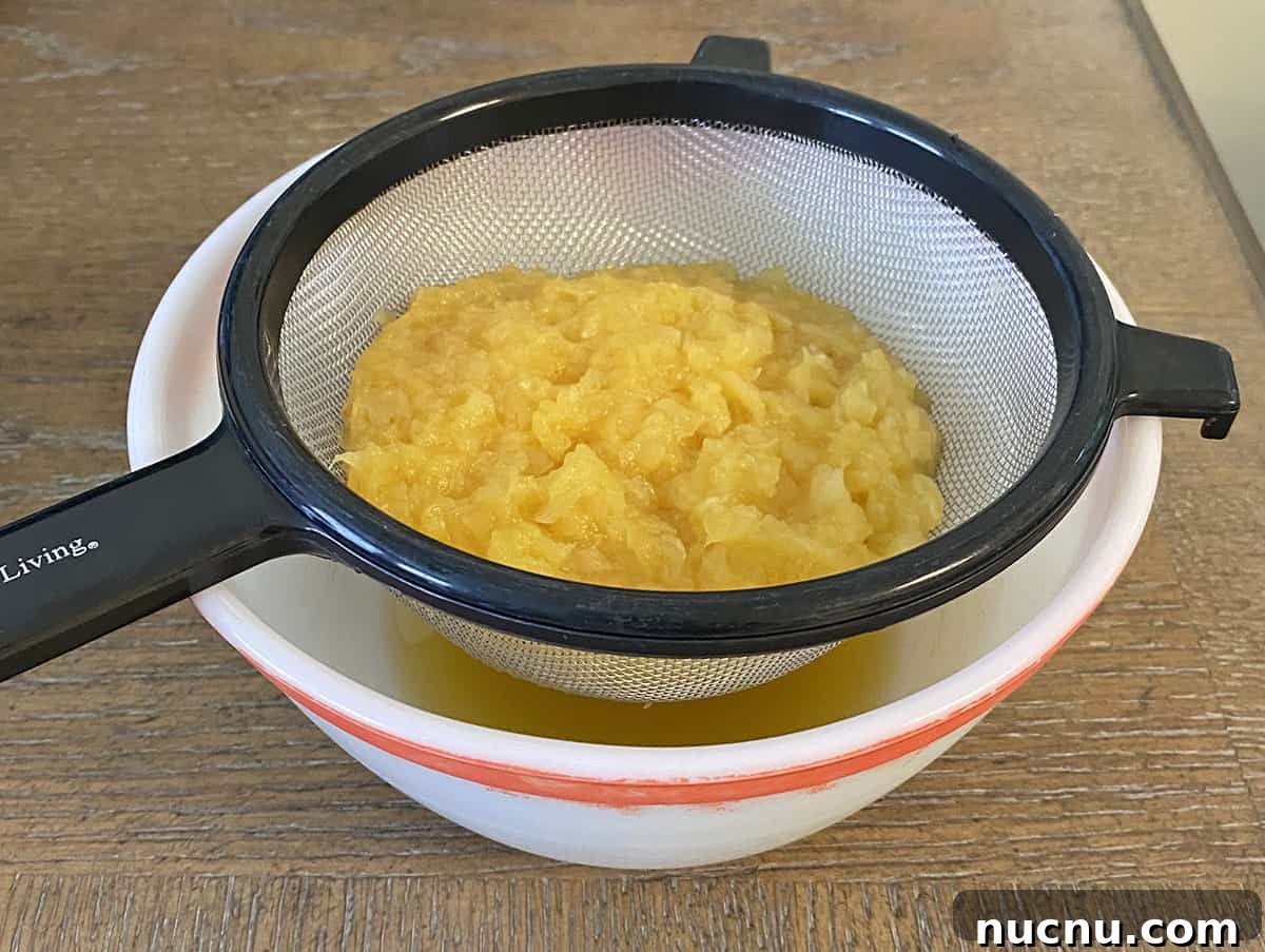 Contents of can of crushed pineapple in a strainer over a bowl to collect the pineapple juice.