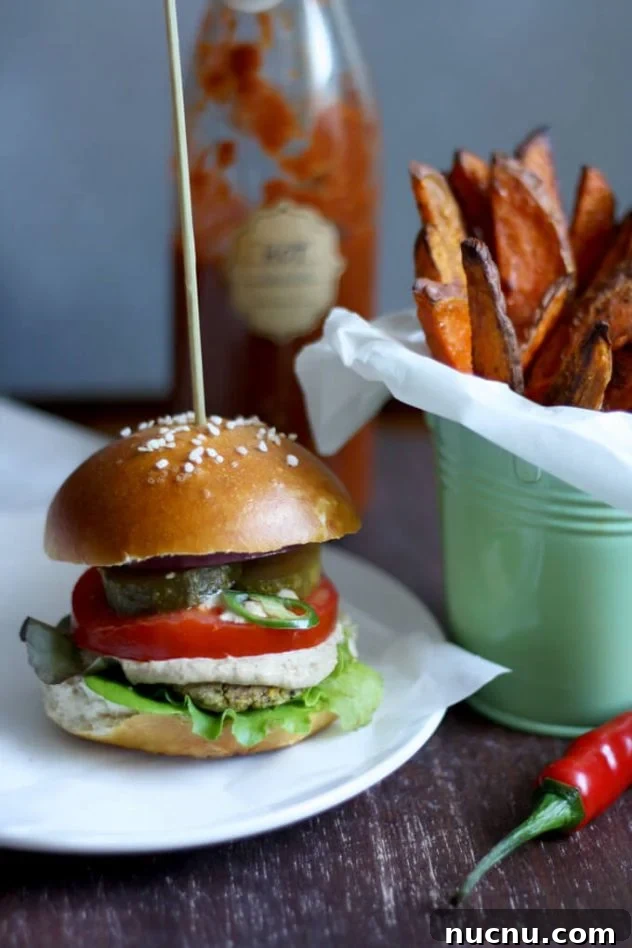 Juicy vegan falafel burger in a pretzel bun served with creamy tahini sauce and crispy and tender sweet potato fries. The best healthy falafel burger I've ever had!