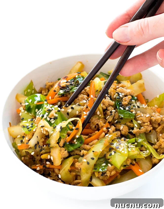 Crack Slaw | chefsavvy.com using chopsticks to eat out of a bowl of sautéed cabbage and ground chicken